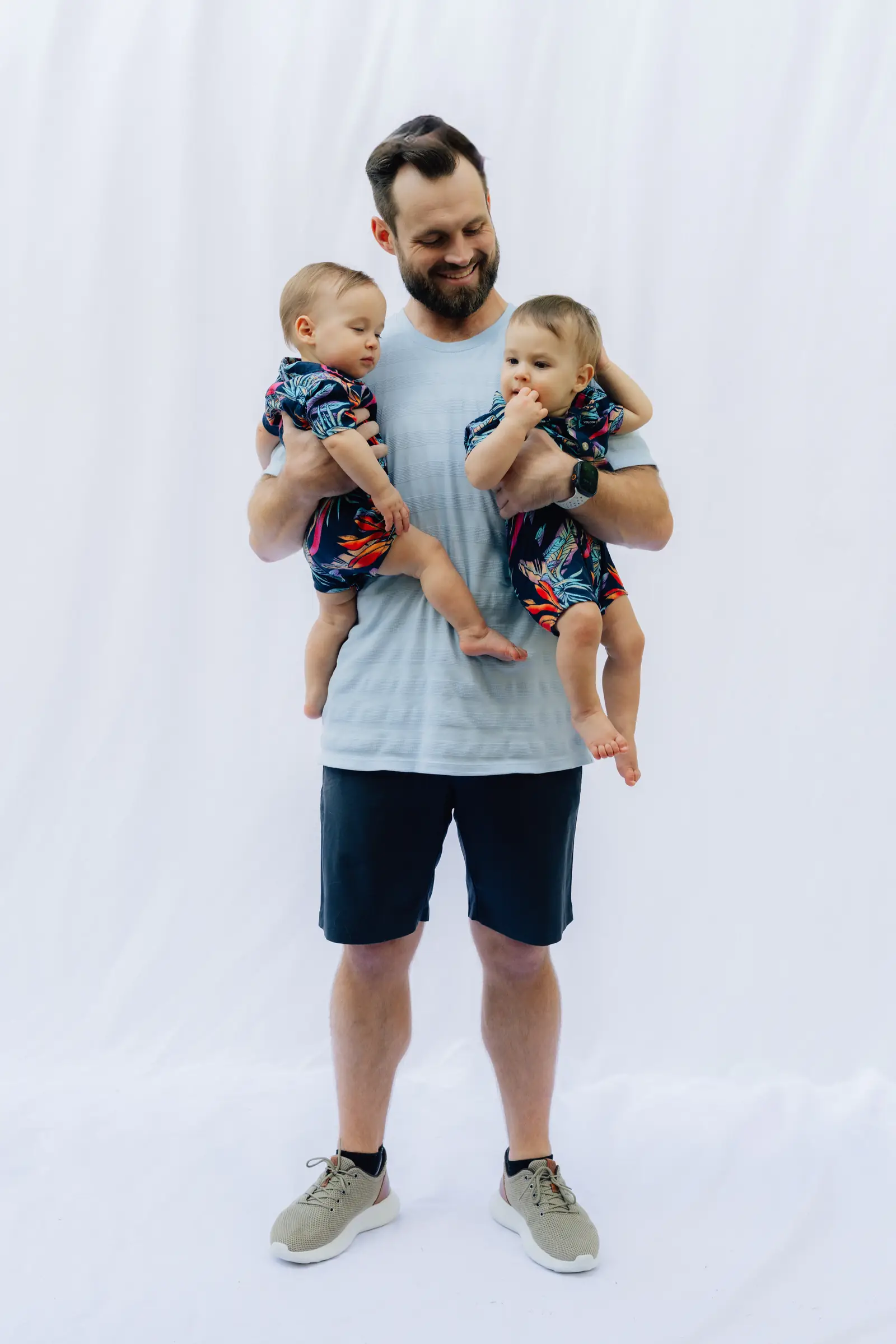 A smiling father holding his two twin babies close